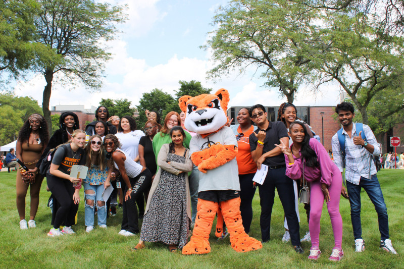 A large group of diverse Governors State University students posing for a photo with the University mascot Jax the Jaguar at the campus block party
