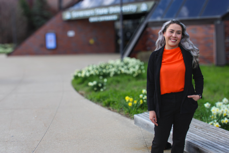 A smiling woman standing in front of Governors State University