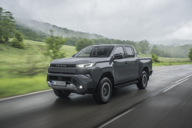 Official Toyota image of the 2026 Hilux BEV driving on a wet road