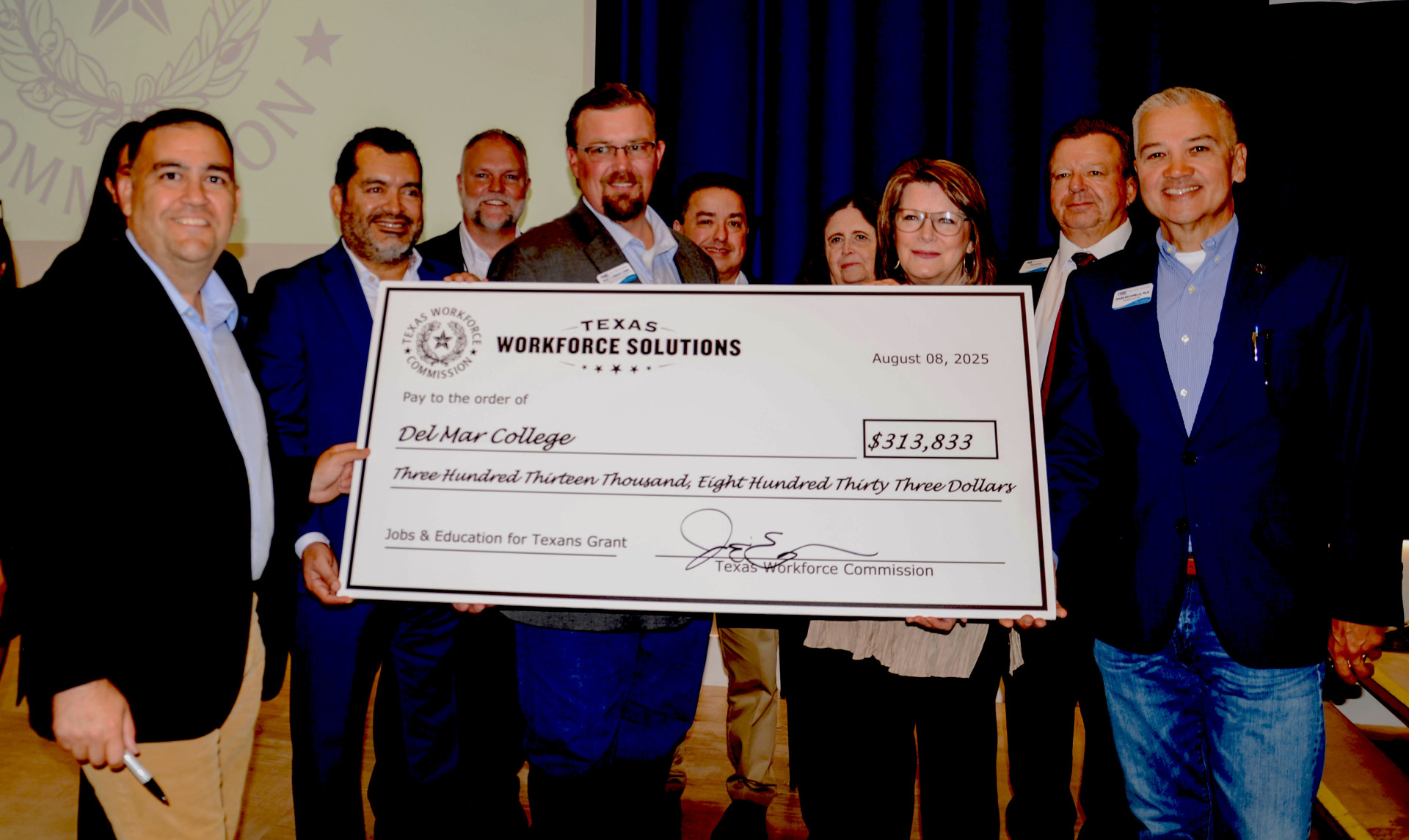TWC JET Grant_DMC Faculty and Administrators with Commissioner Joe Esparza - Del Mar College representatives pose with Commissioner Representing Employers Joe Esparza with the Texas Workforce Commission (left) after he signed an oversized check symbolizing the more than $313,000 Jobs & Education for Texans (JET) grant awarded to the Automotive Applied Technology Program. The college purchased state-of-the-art equipment to train automotive repair and maintenance technicians needed by South Texas automotive industry employers, including hands-on skills training as part of career and technical education (CTE) partnerships with area high schools. Pictured with Commissioner Esparza are JET Advisory Board member Mario Lozoya and appointed by Lt. Gov. Dan Patrick (second from left); Chad Magill, District Liaison for Texas State Senator Adam Hinojosa (District 27); Paul Creacy, DMC Architecture, Aviation and Automotive Department Chair; Dr. Leonard Rivera, Associate Vice President of Dual Enrollment and Continuing Education; Dr. Jonda Halcomb, Vice President and Chief Academic Officer; DMC Board of Regents Chair Carol A. Scott; Dean of Workforce Programs and Corporate Services Dan Korus; and Dr. Mark Escamilla, DMC President and Chief Executive Officer. (Credit: DMC College Relations) TWC JET Grant_DMC Faculty and Administrators with Commissioner Joe Esparza