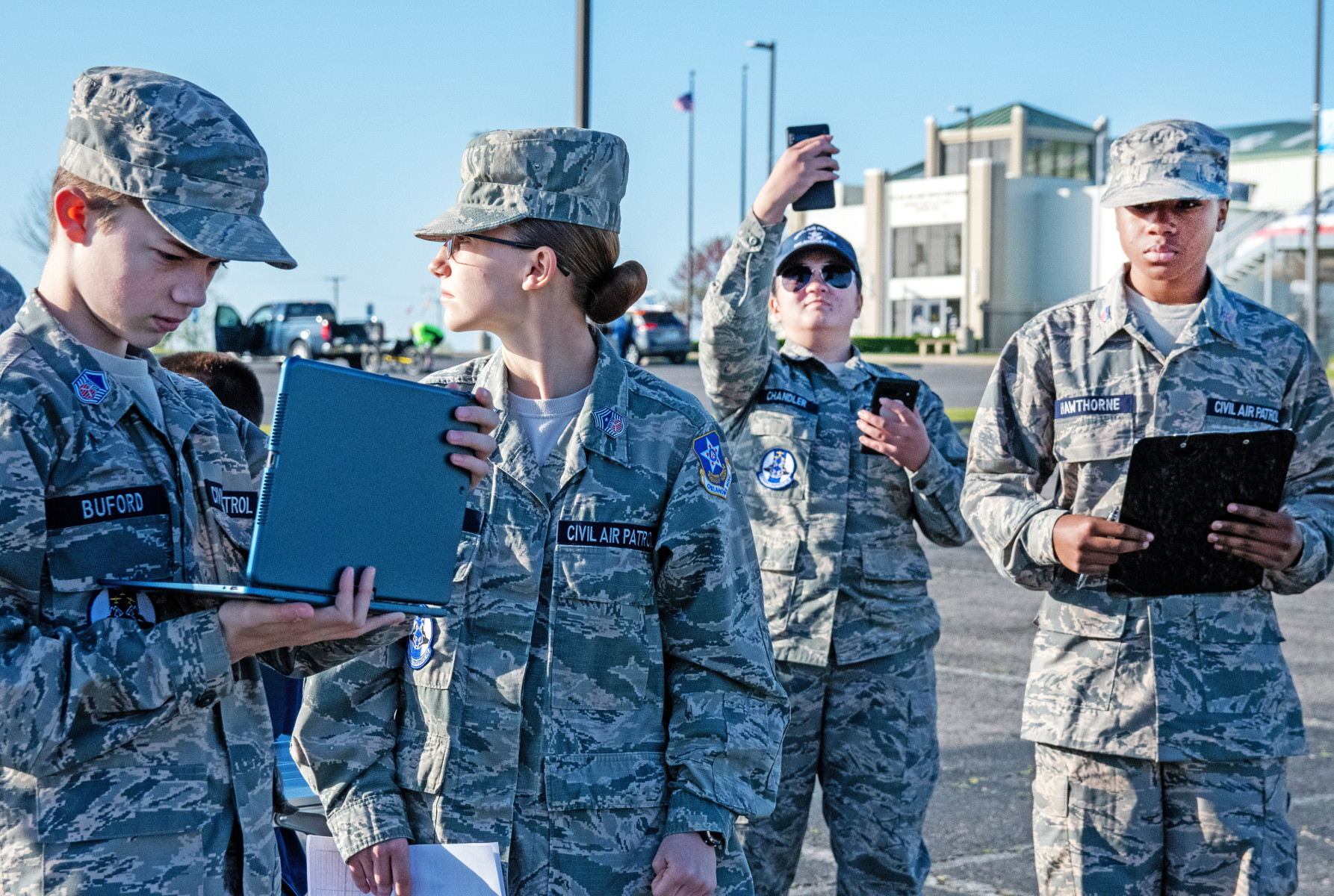 Four cadets with laptops and a phone stand collecting data.