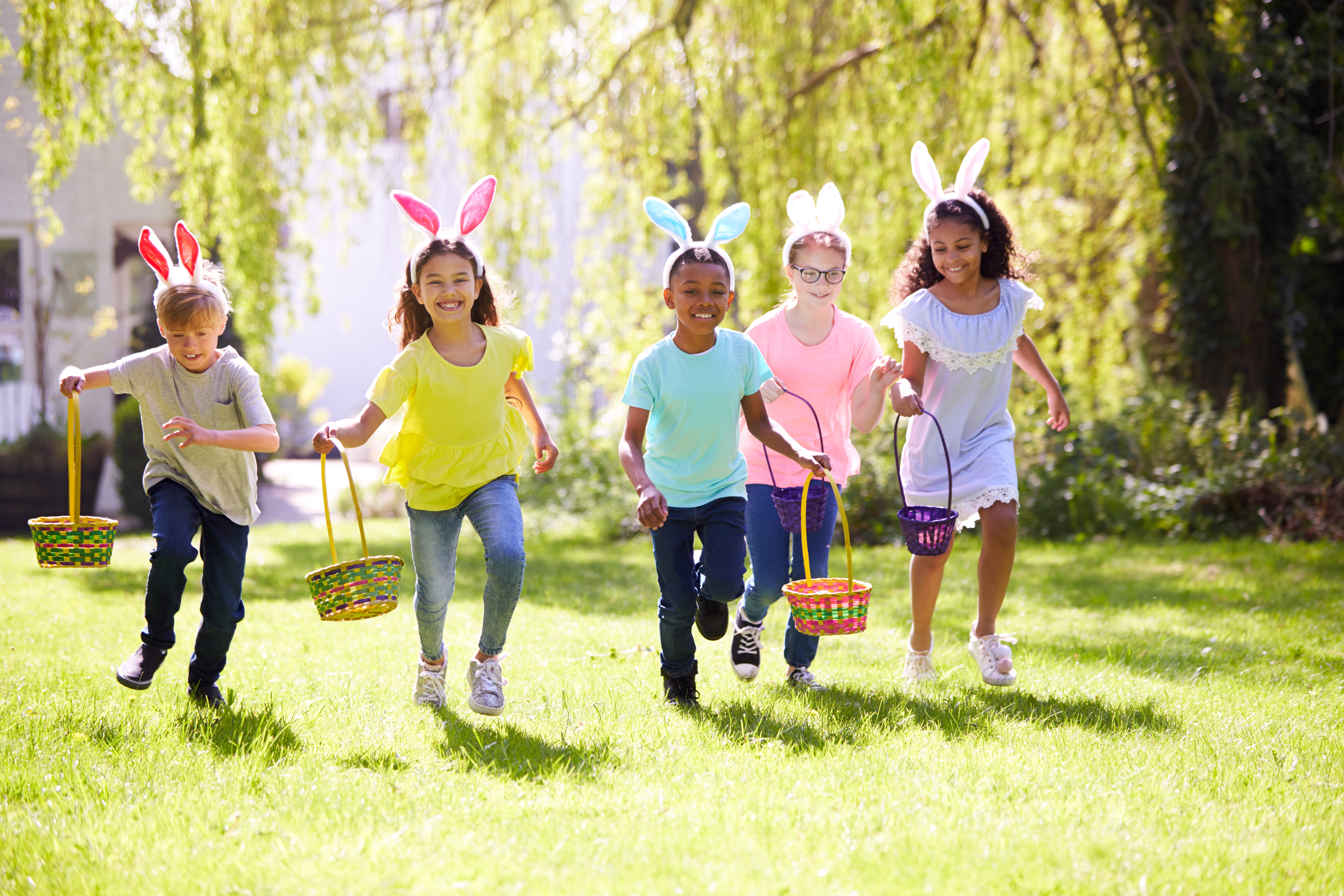 Group Of Children Wearing Bunny Ears Running To Pick Up Chocolate Egg