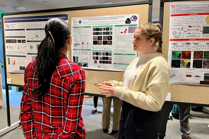 Madelyn Arzt (right), a research associate III at Cedars-Sinai, presents her abstract.
