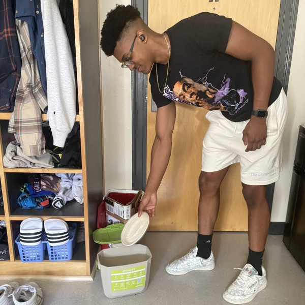 A student uses a compost bin.