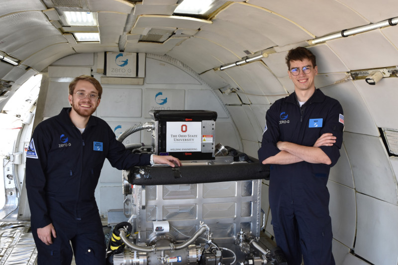 Aaron Brimmer and Will McAuley stand alongside their machine in the Zero-G chamber.