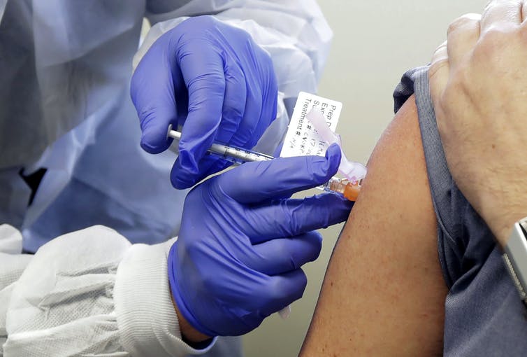 A patient receives a shot in a clinical trial for a COVID-19 vaccine.