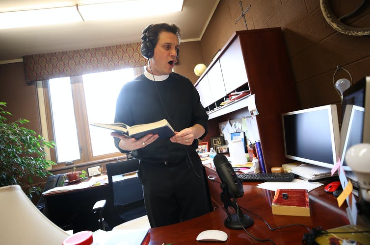 The Rev. Philip Dinwiddie sings to a pre-recording of mass at St. James Episcopal Church in Grosse Ile, Michigan.