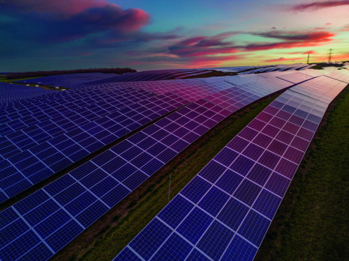 Solar cell power station on green field, electric pylon and power lines on agricultural field during sunset. Eco power, Photovoltaic, Alternative electricity source, Solar panel generating electricity clean energy at sunset