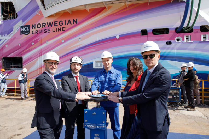 Norwegian Cruise Line and Fincantieri S.p.A's representatives celebrate the float out of the all-new Norwegian Aura, NCL's first ship to be built at Fincantieri's Monfalcone shipyard. From left to right: Emanuele Truant, Norwegian Prima Project Manager of Fincantieri; Andrea Marongiu, Senior Director, Newbuilding Project Owner NCL; Claudio Wenzlich, Valve Operator at the Monfalcone shiyard; Lisa Scaravetti; HVAC Manager at Fincantieri; Cristiano Bazzara, Director of the Monfalcone shipyard. © Rocket Aerial LLC  (Image at LateCruiseNews.com - April 2026)