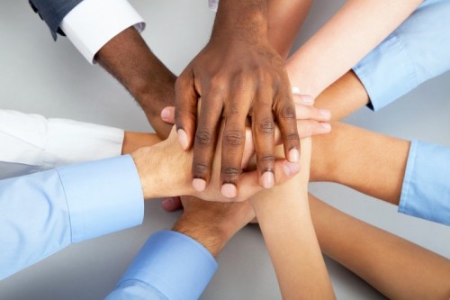 stock-photo-closeup-of-business-team-putting-their-hands-on-top-of-each-other-125165846.jpg