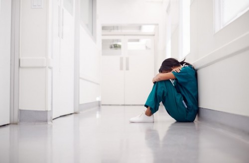 stock-photo-stressed-and-overworked-female-doctor-wearing-scrubs-sitting-on-floor-in-hospital-corridor-1637183134.jpg