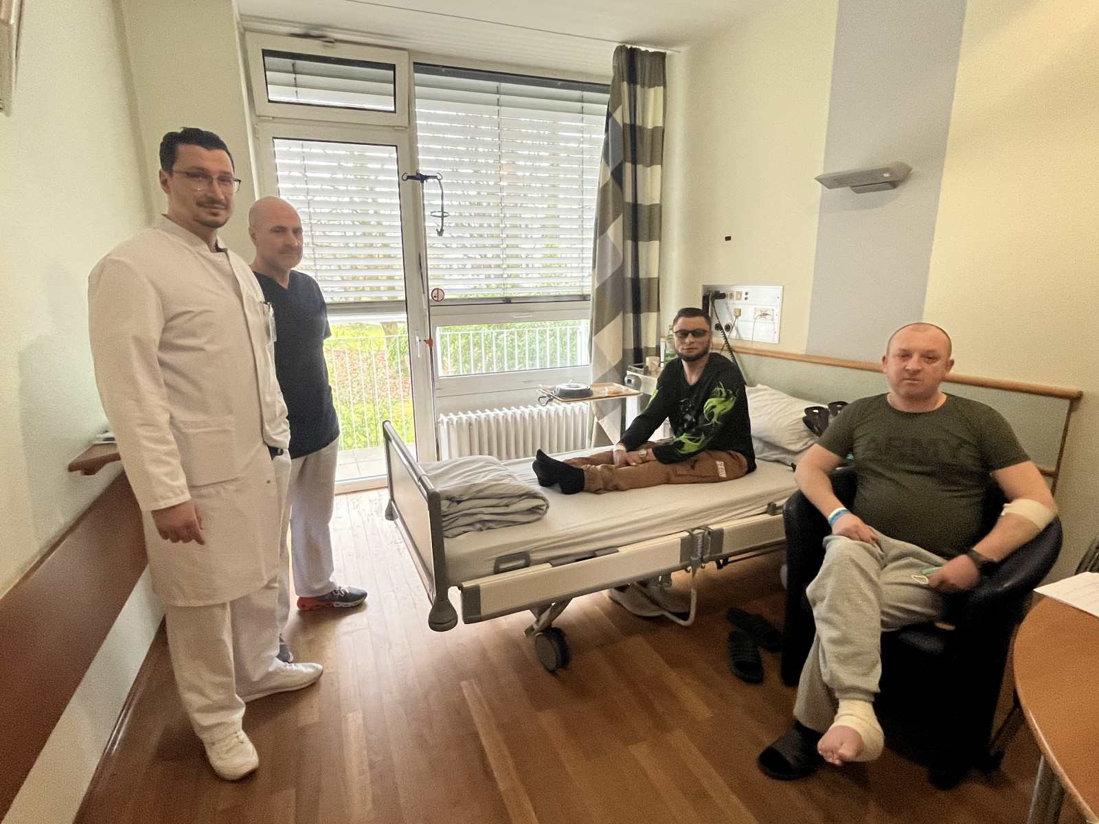 Die beiden ukrainischen Soldaten, Yevhen Zelemskyl (34),2.v. r., und Anton Khomaiko (40) rechts, werden seit Mitte M&auml;rz im Sana Krankenhaus Benrath von Chefarzt Dr. Alexander Olk (2. v. l.) und Oberarzt Dr. Graviel La Rosa (links) behandelt. Foto: Sana
