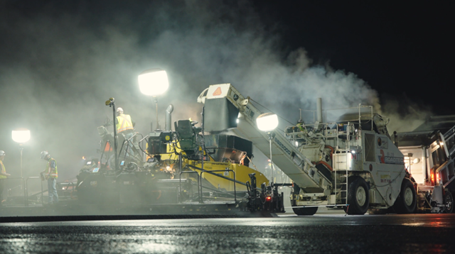 Légende de l’image : Des équipes travaillent de nuit pour appliquer le revêtement de la piste.