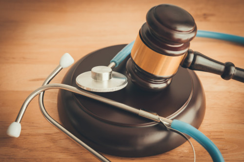 Judge hammer gavel and doctor stethoscope on wooden table background in courtroom. Health law, medical law rules, regulations in the health care industry and its patients, medical malpractice concept.