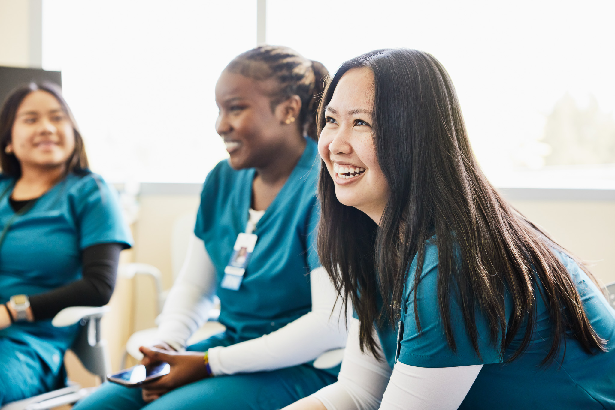 Medium shot of smiling female nurse in medical team meeting in hospital conference room