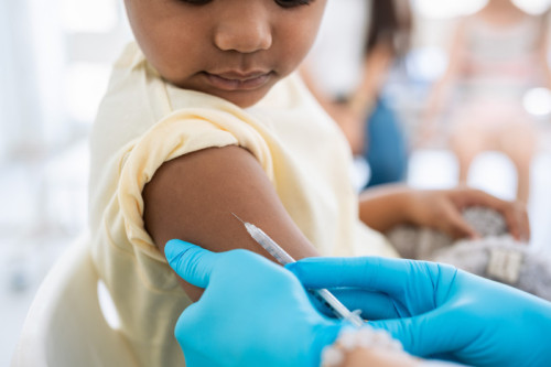 Immunisation. Protecting children from diseases. Close-up nurse in medical gloves giving injection to little patient. Brave boy getting a flu shot at doctor&#039;s office and looking at needle