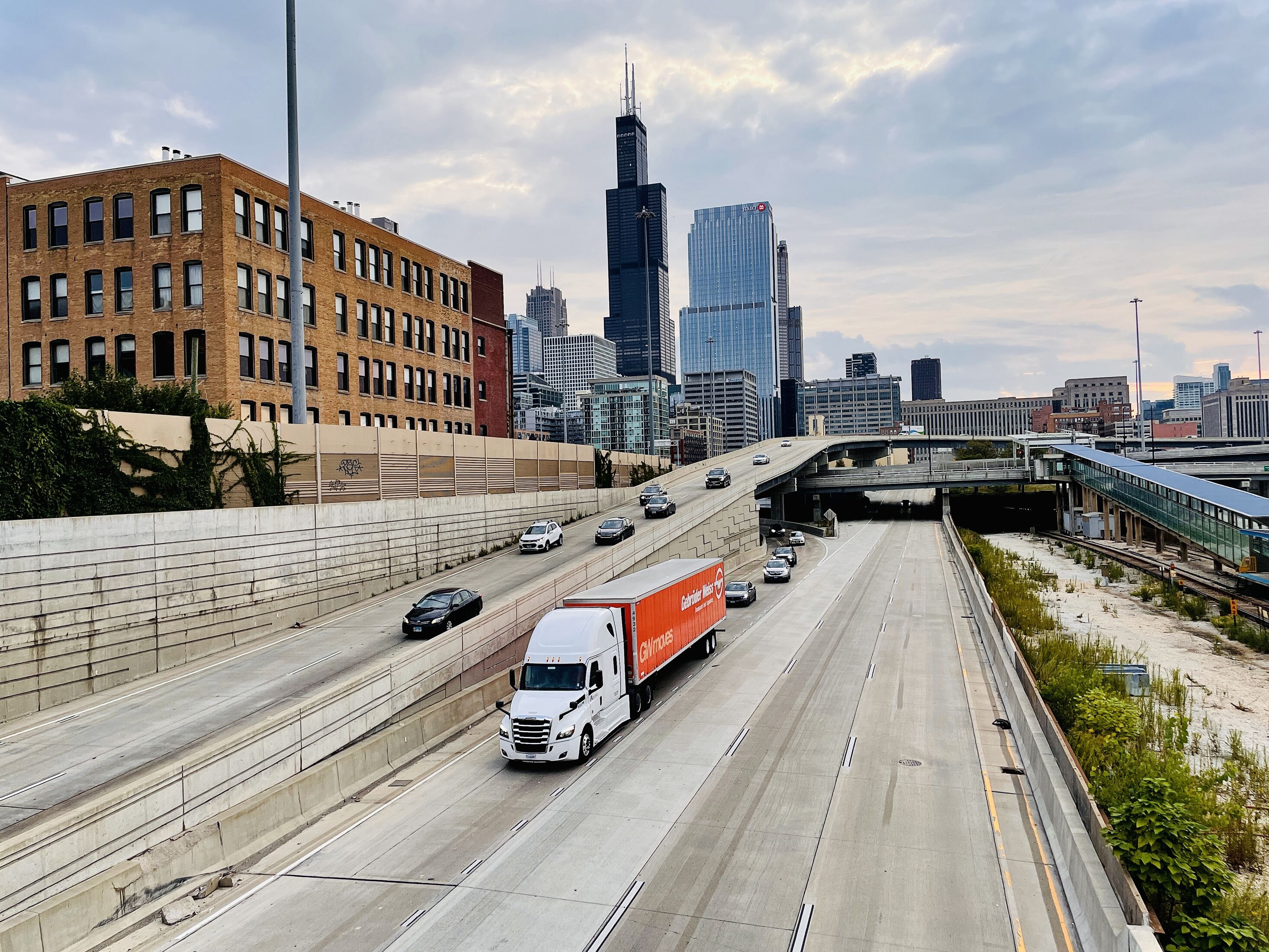 Gebrüder Weiss truck driving on a busy Chicago highway with skyscrapers in the background