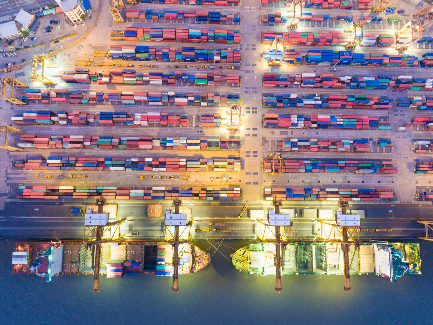 Aerial view of container terminal with cargo ships, cranes, and stacked containers at a busy port