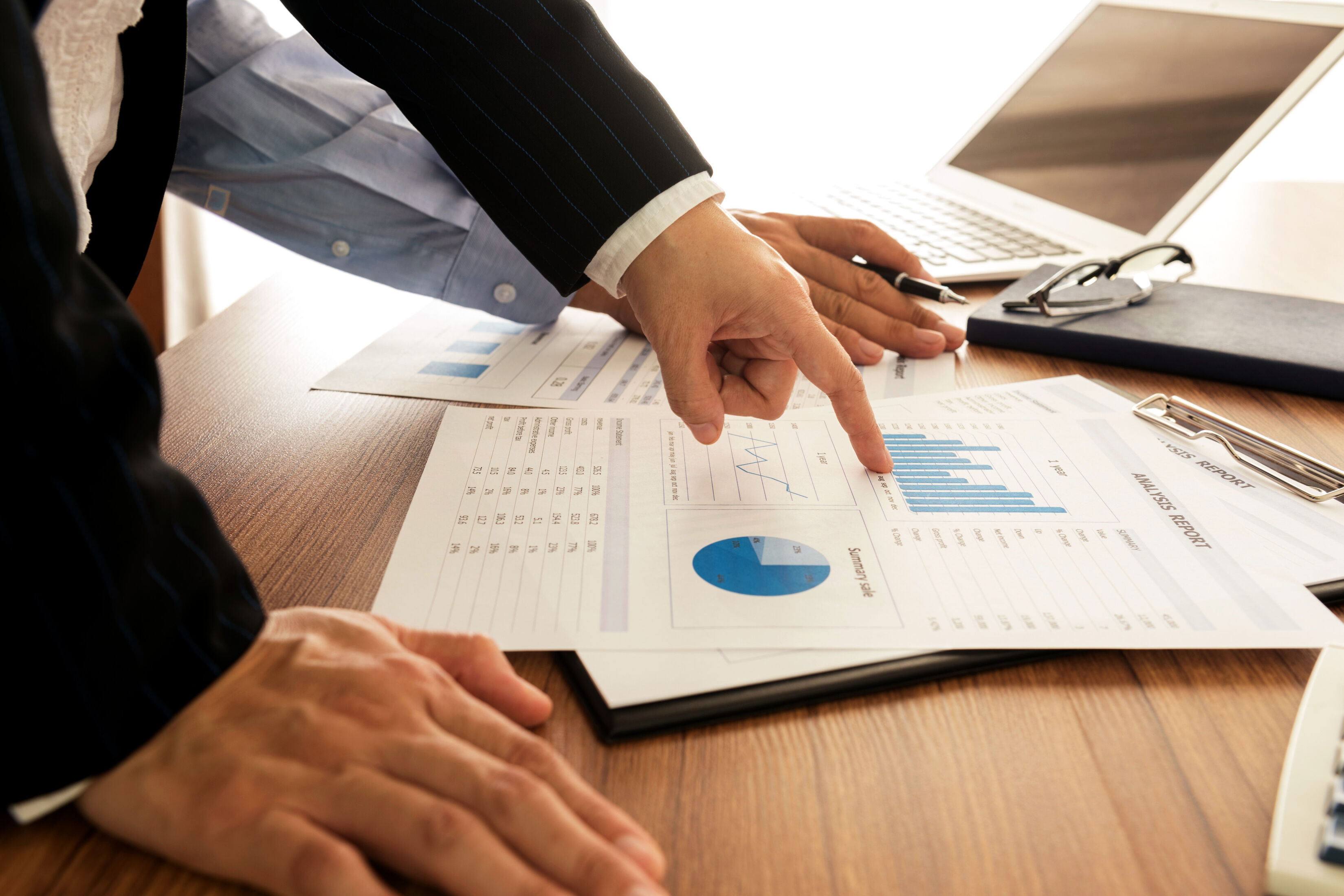 Two professionals reviewing printed charts and graphs during a logistics meeting.